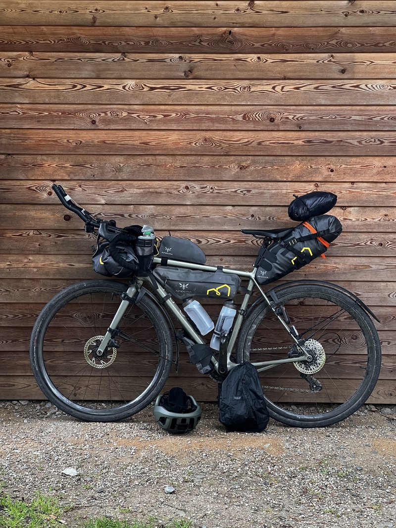 A gravel bike packed for an adventure, leaning against a wooden wall.