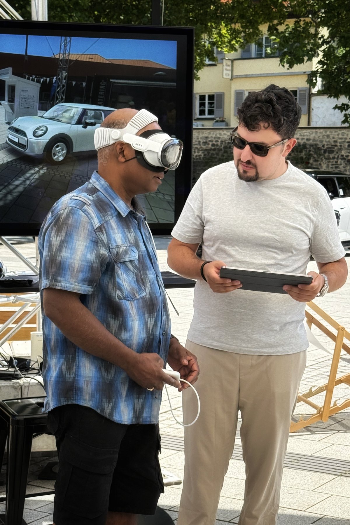 Philip holding a tablet beside a participant trying an immersive MINI demo with a headset.